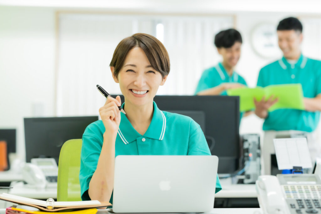 記事内イメージ画像_笑顔でパソコン前に座る女性介護士