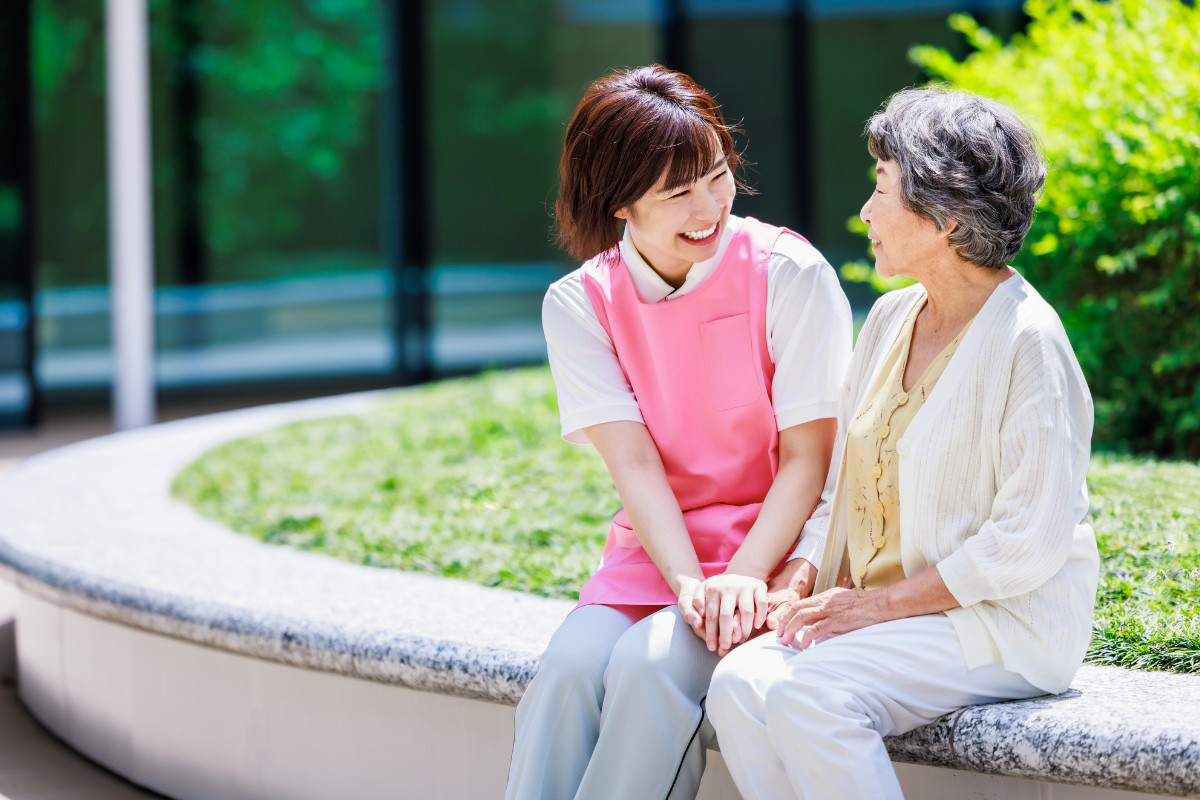 記事サムネ画像-介護士と高齢者が笑顔で座っているイメージ