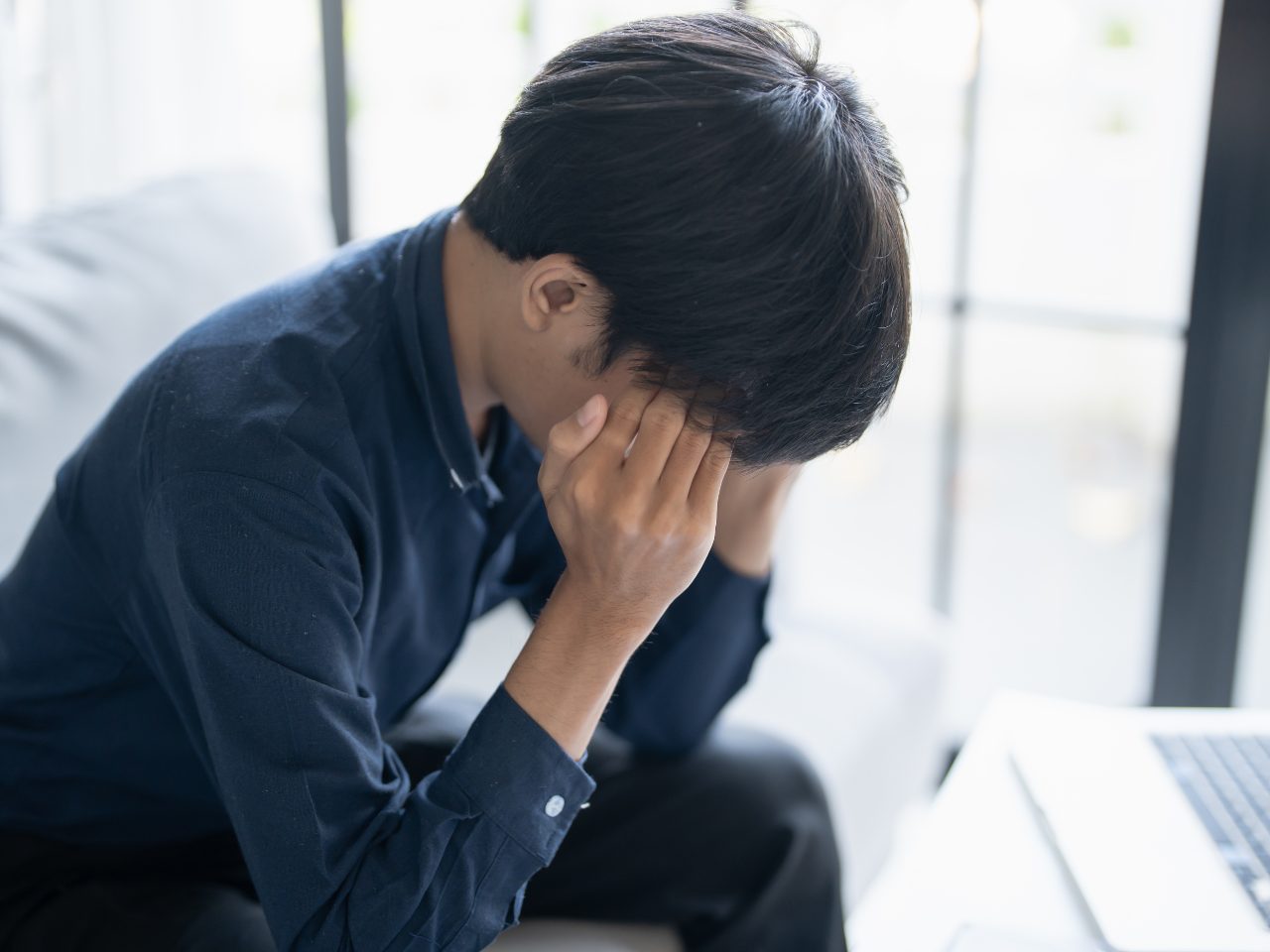 手で顔を覆う男性
