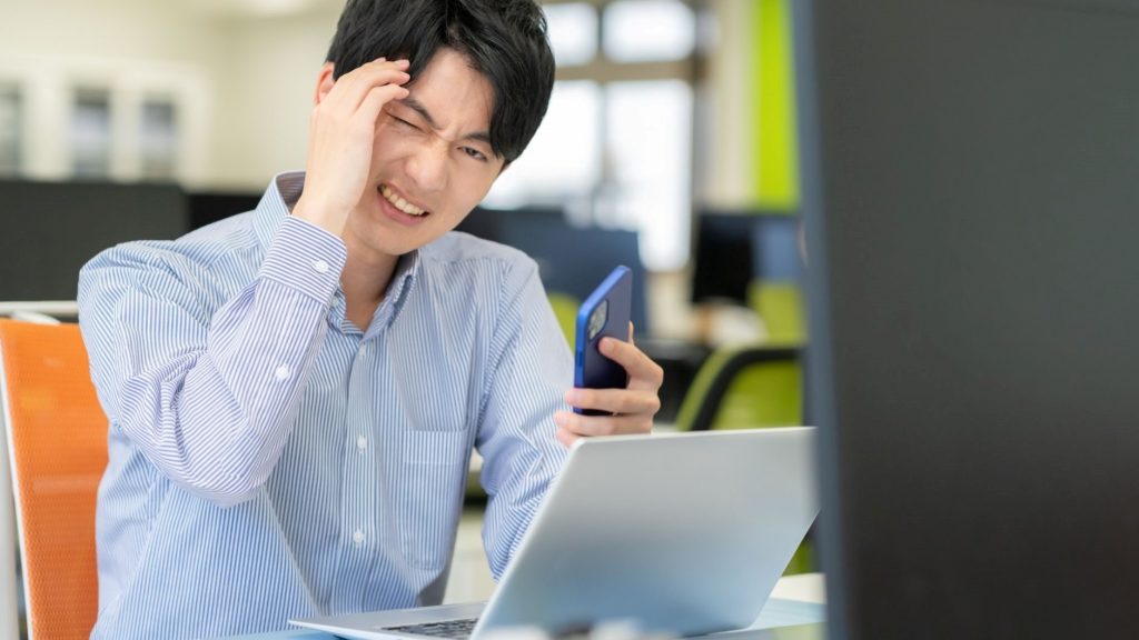 パソコンの前で困っている男性