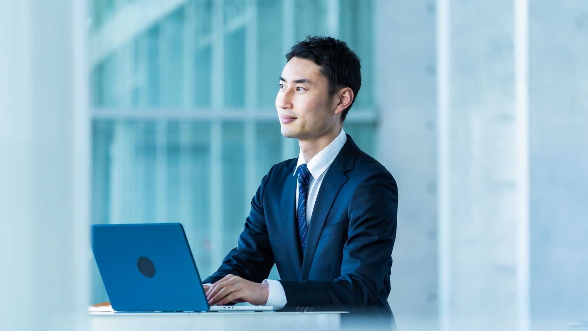 青いPC、スーツの男性