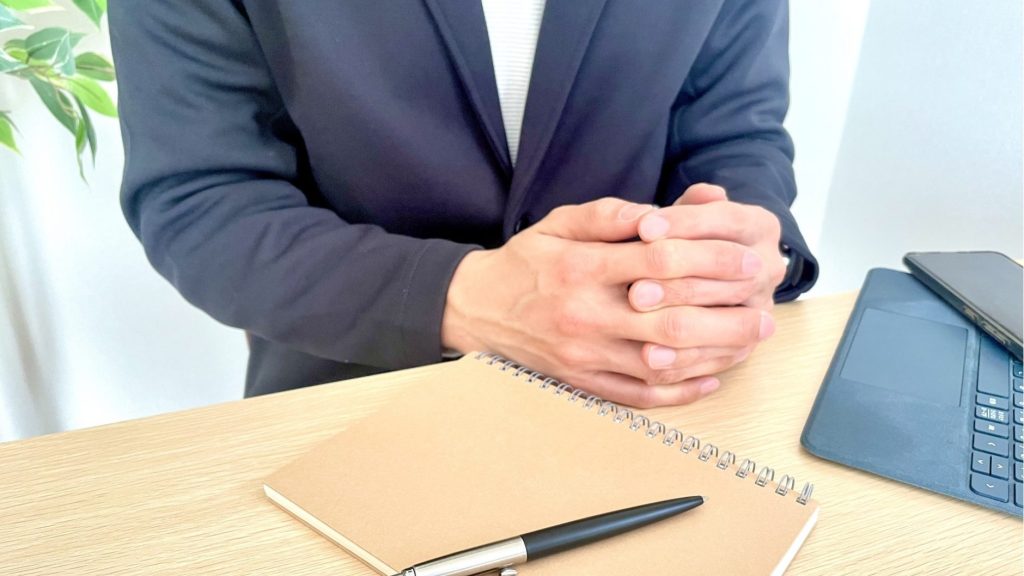 ジャケットを着用して指を組んでいる男性