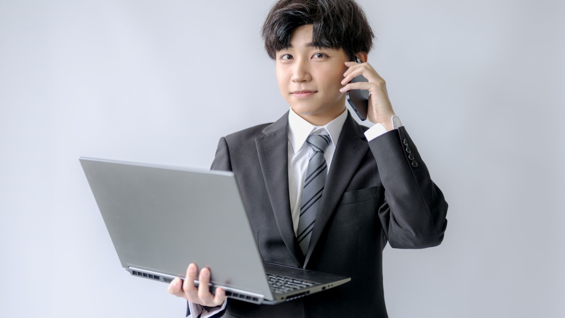 電話を掛けながらPCを持ったスーツの男性