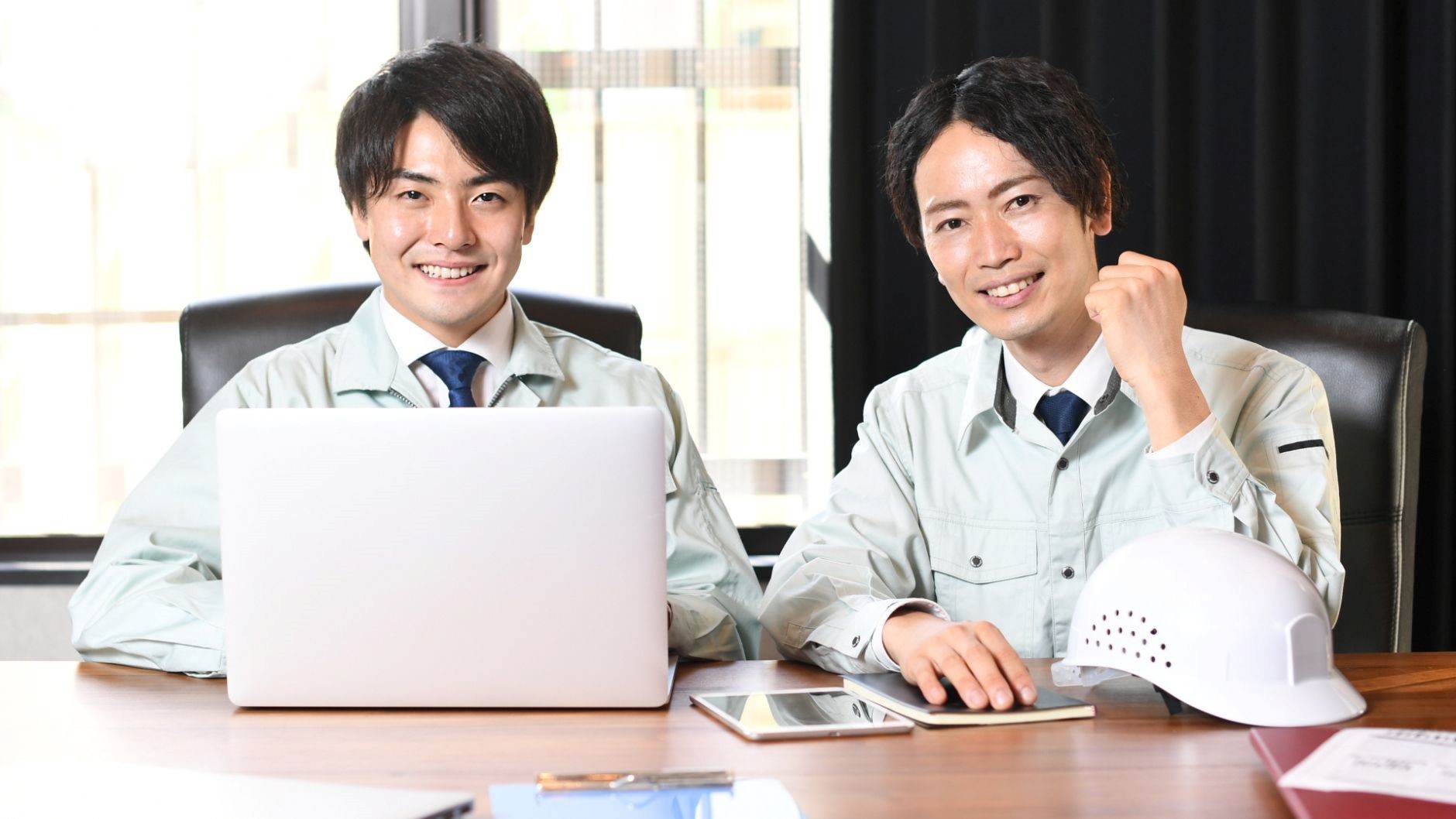 作業着男性2人、ヘルメット、PC