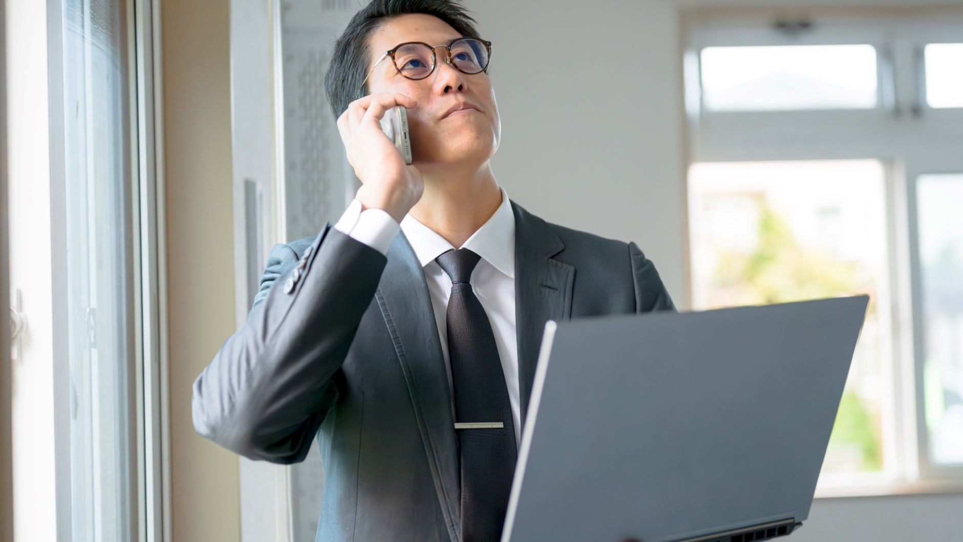 PC、スマホで電話、眼鏡の男性