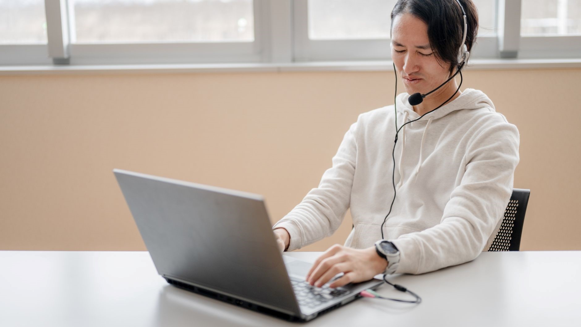 ヘッドセット、PC、白いパーカーの男性