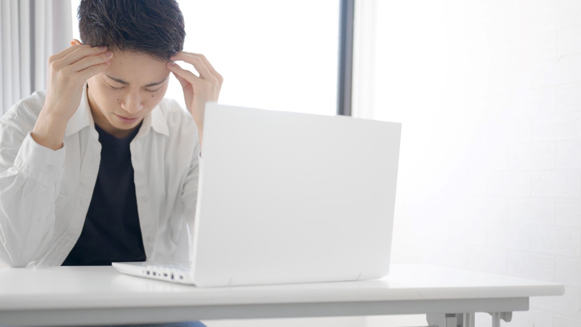 頭を抱える男性、PC