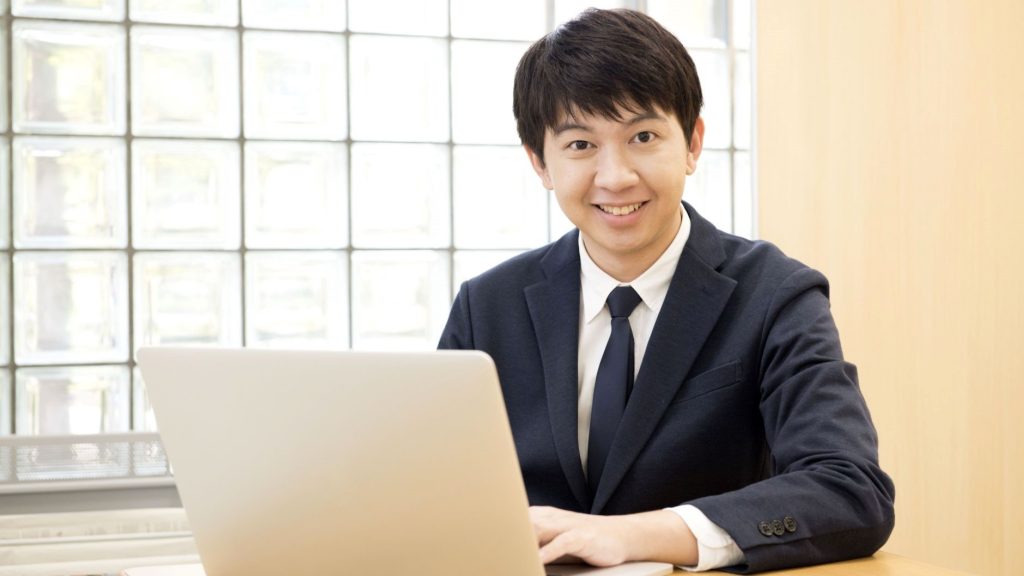 PC操作をしながら笑顔を向ける男性