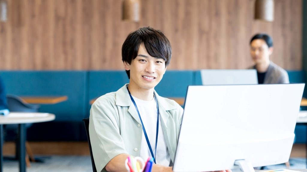 パソコン越しに笑顔を向ける男性