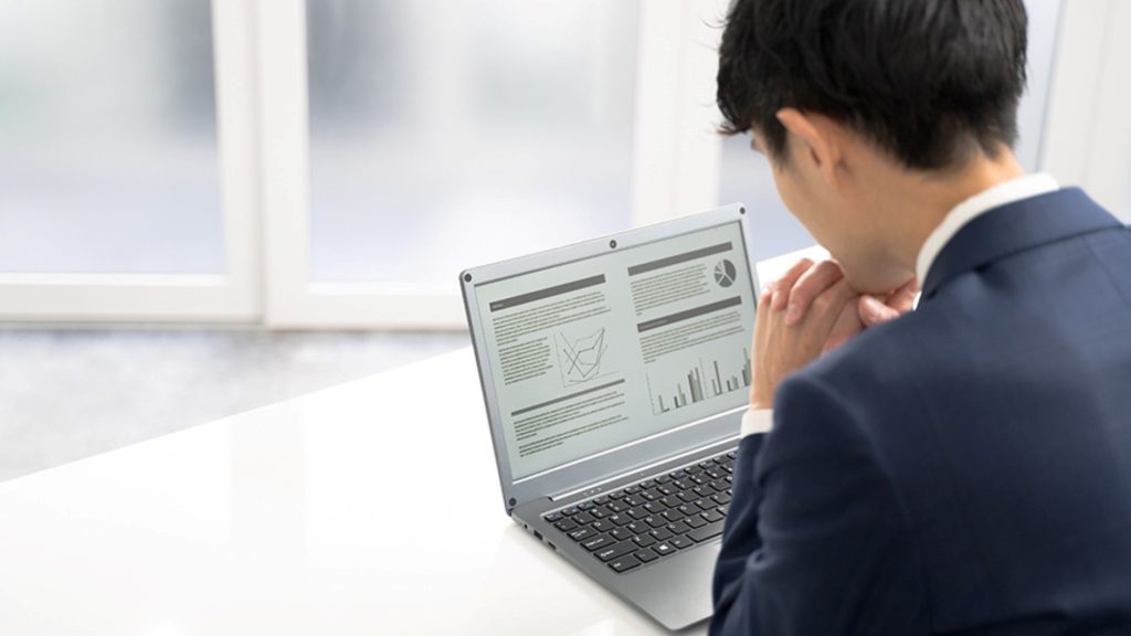 PC画面を見ながら考える男性の後ろ姿