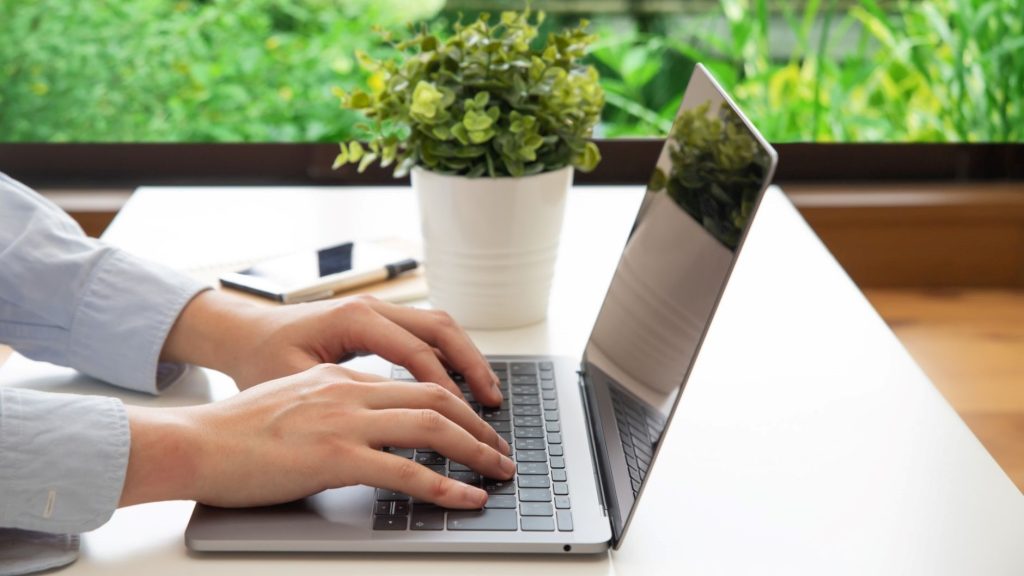 PCのキーボードに置かれる手を横から見た写真