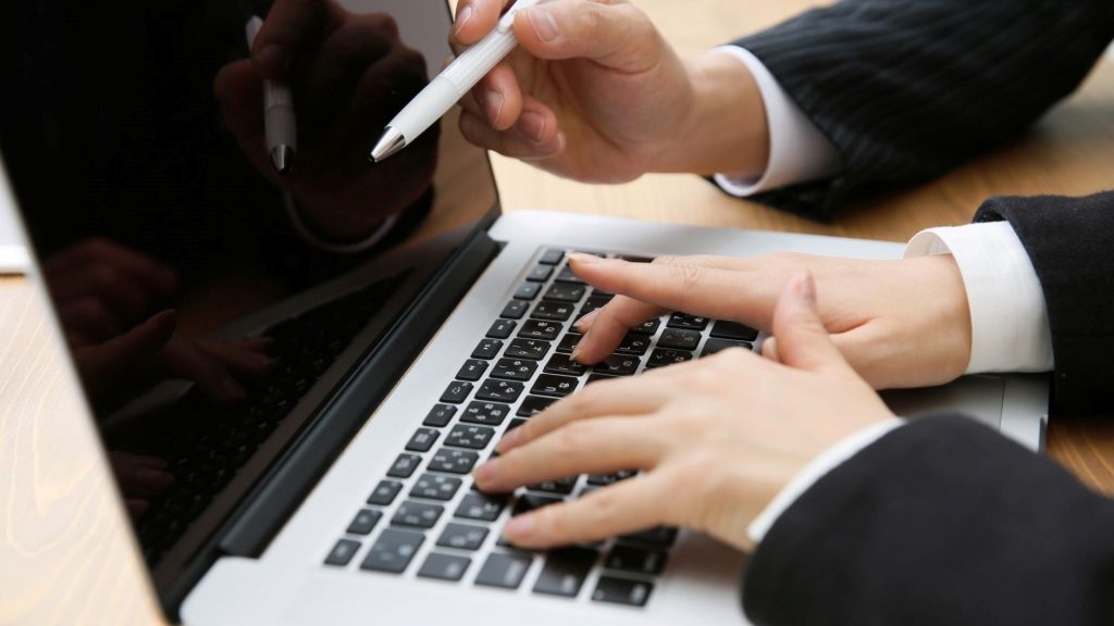 PC画面にペンを向ける手とキーボードを打つ手