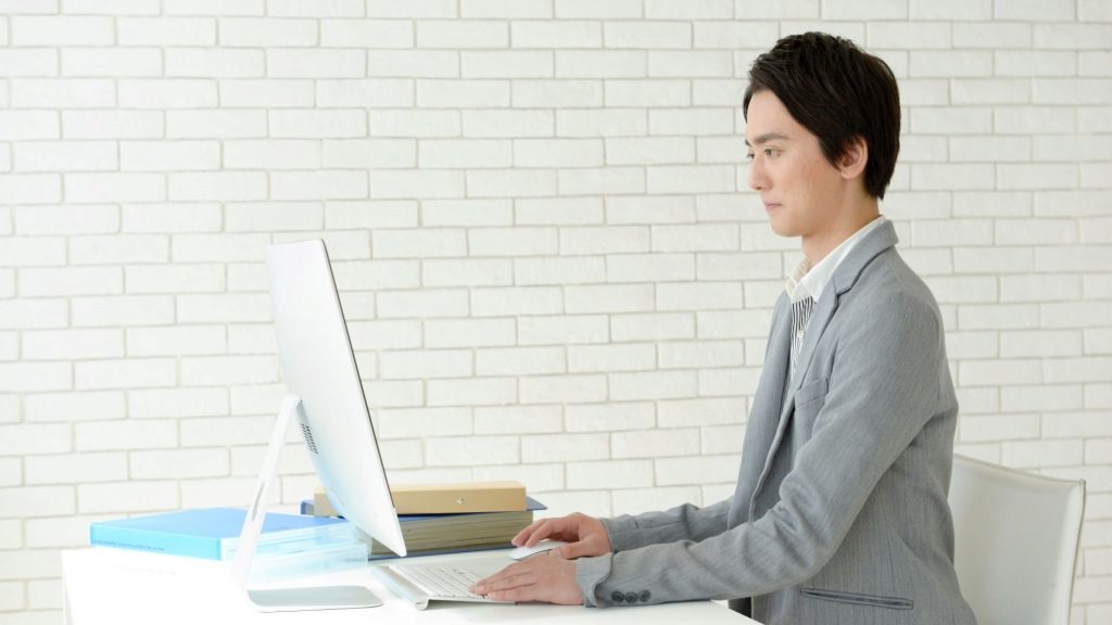 PC画面に向かって作業をする男性の横姿