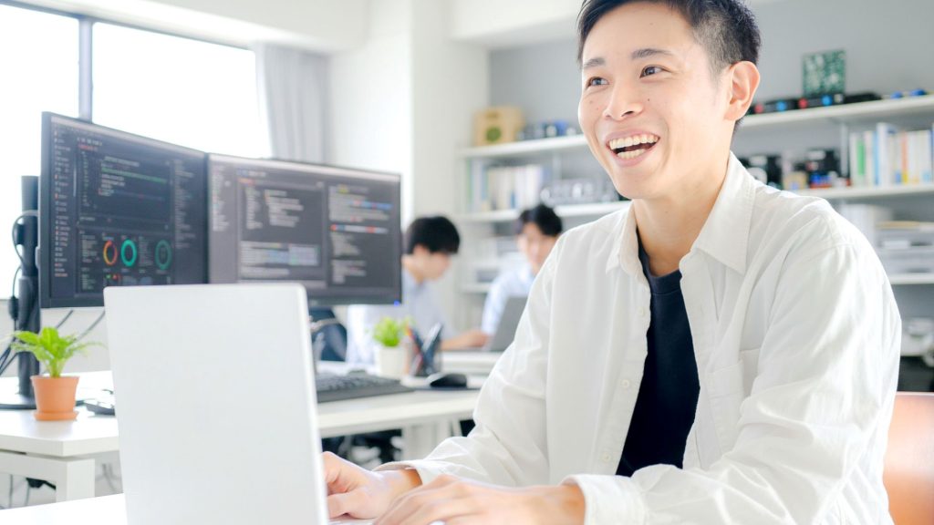 PCを操作しながら笑顔になる男性