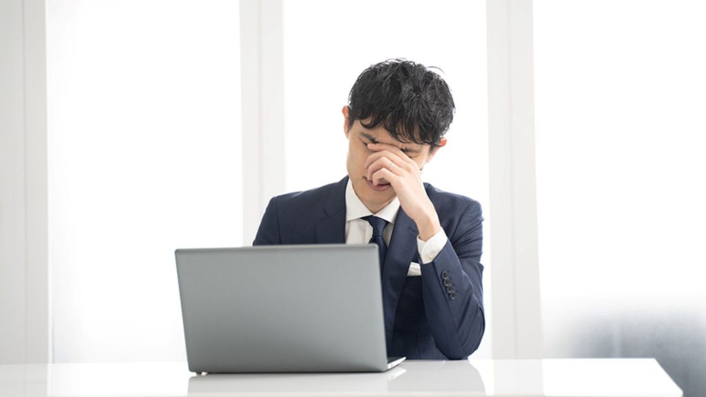 PCの前で頭を抱える男性