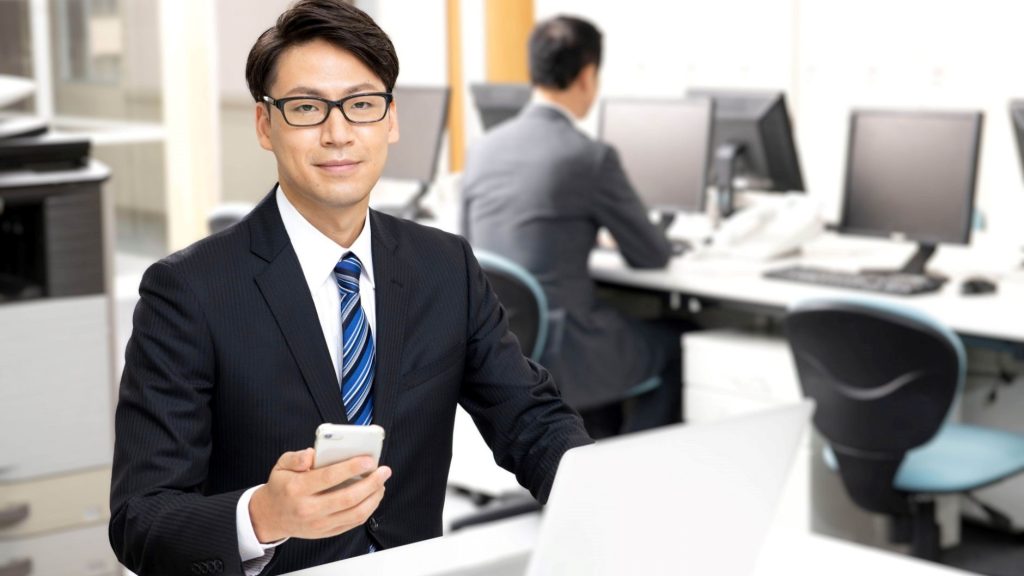 スマホを片手に持つ眼鏡をかけた男性