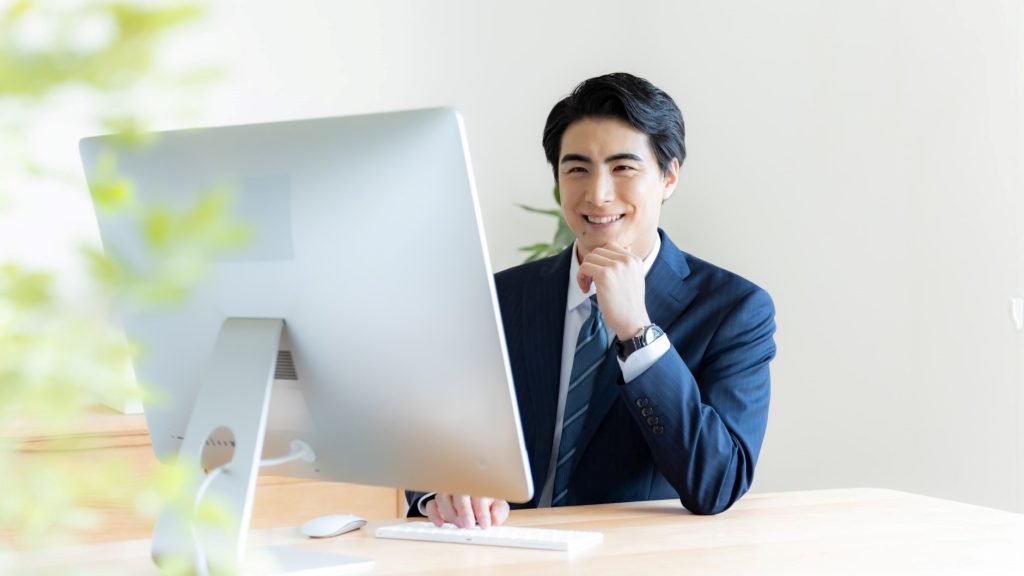 PCの前で笑顔になる男性