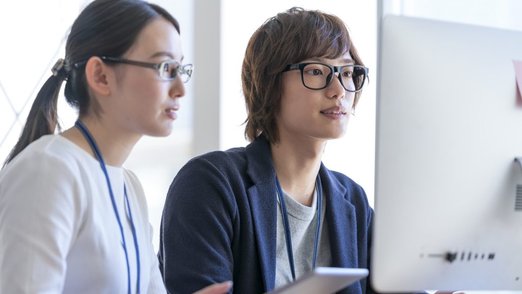 パソコンのモニタを見る若い男女