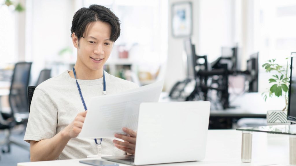 PCの前で書類を確認する男性