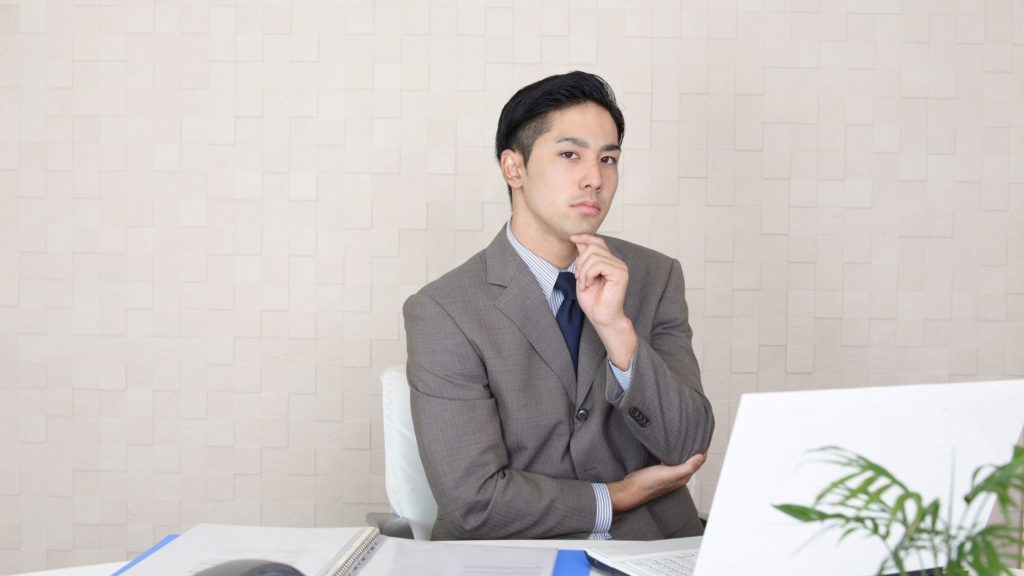 PCの前であごに手を添えて悩む男性