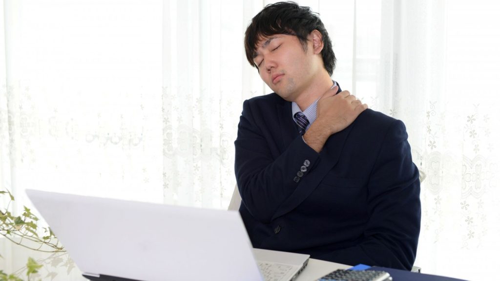 PCの前で肩をほぐす男性