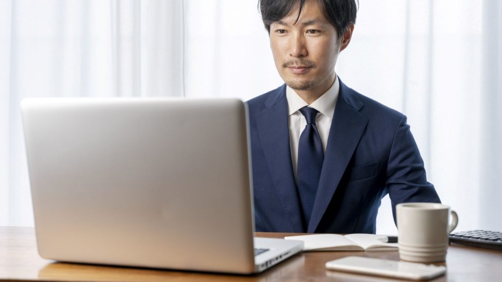 部屋の中でPCを見るスーツ姿の男性