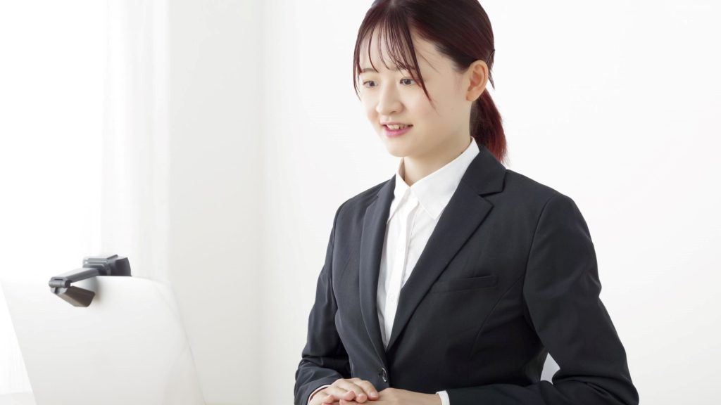 PCカメラを見ながら会話をするスーツ姿の女性