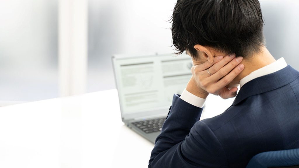 PCの前で肘をつく男性の後ろ姿