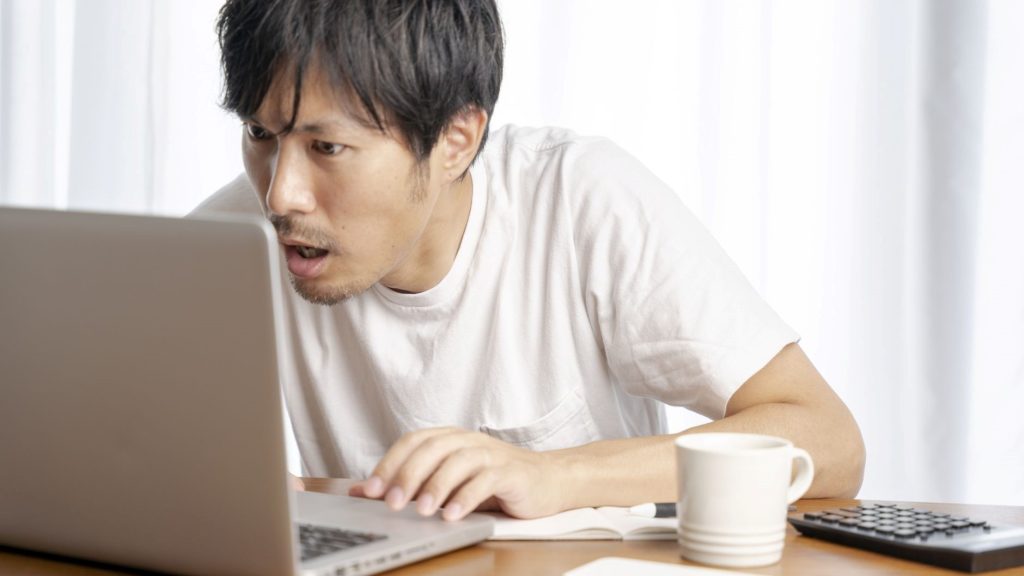 前のめりでPC画面を見ている男性