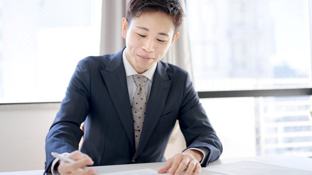 笑みを浮かべつつ書類を確認する男性