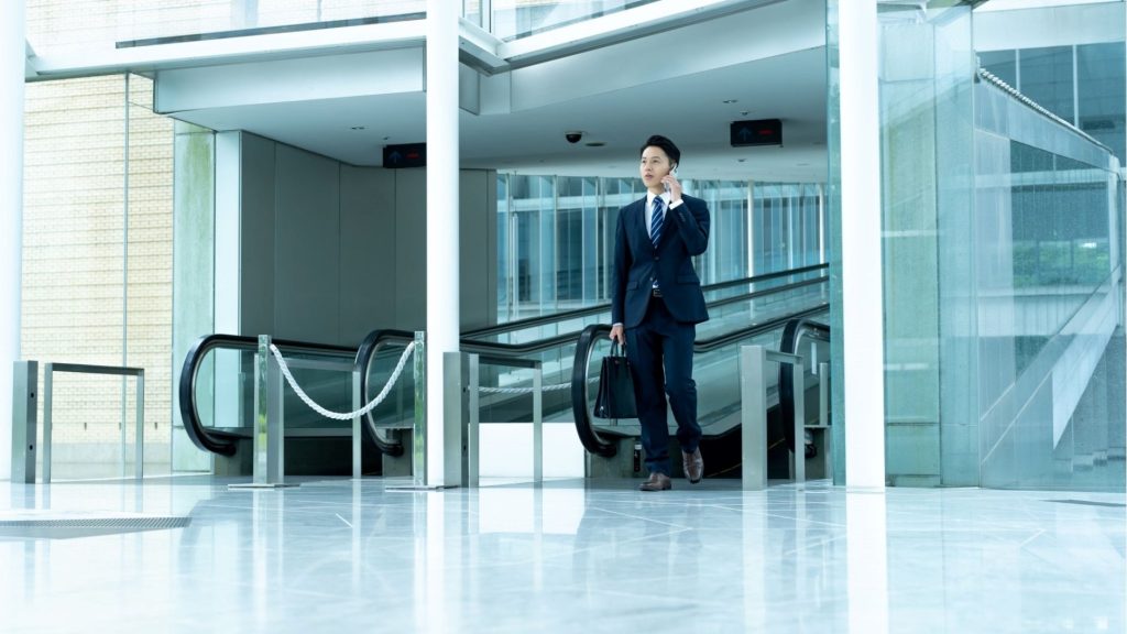 電話をしながらエスカレーターを降りる男性