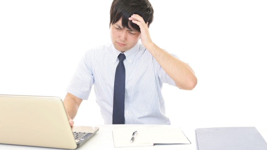 PCの前で額に手を添える男性