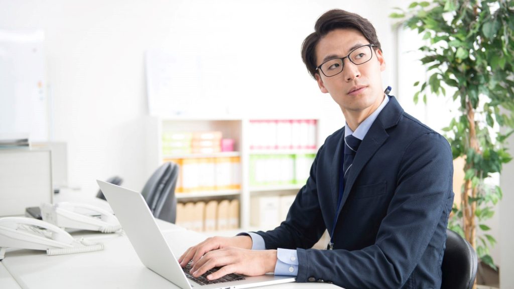 PCに手を添えて振り向く男性