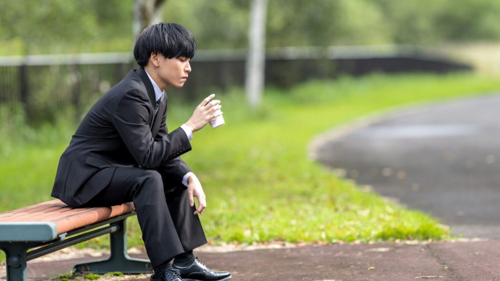 ベンチでコーヒーを飲む男性
